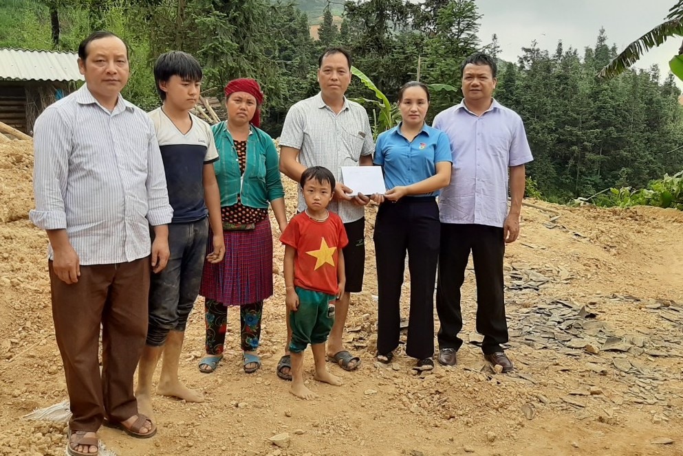 Đồng chí Phan Thị Bình - Chủ tịch Liên đoàn Lao động huyện Yên Minh (đứng thứ 2, từ bên phải sang) - trao hỗ trợ 2 triệu đồng cho gia đình đoàn viên công đoàn Sùng Mí Xá. Ảnh: Tuấn Anh.