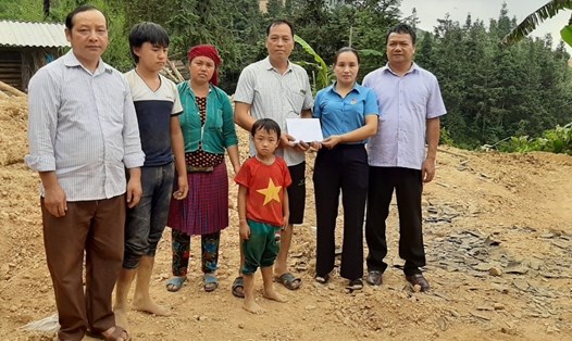 Đồng chí Phan Thị Bình - Chủ tịch Liên đoàn Lao động huyện Yên Minh (đứng thứ 2, từ bên phải sang) - trao hỗ trợ 2 triệu đồng cho gia đình đoàn viên công đoàn Sùng Mí Xá. Ảnh: Tuấn Anh.