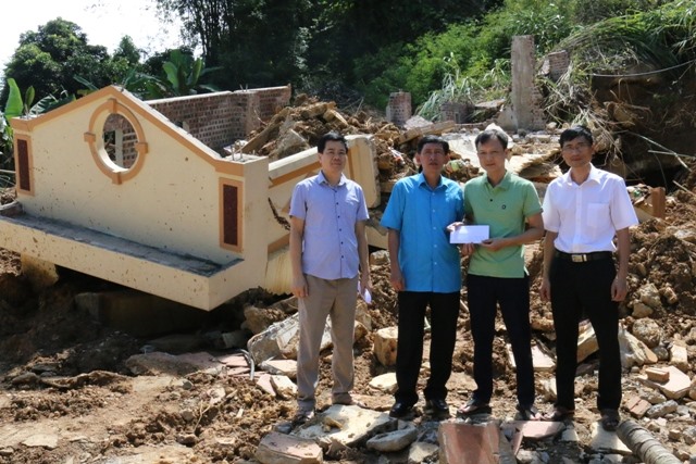 Đồng chí Nguyễn Văn Chung, Tỉnh ủy viên, Chủ tịch Liên đoàn Lao động tỉnh Hà Giang (thứ 2 từ trái qua) trao hỗ trợ tới gia đình anh Huấn ngay tại nơi ngôi nhà bị sập. Ảnh: Trí Hiếu.