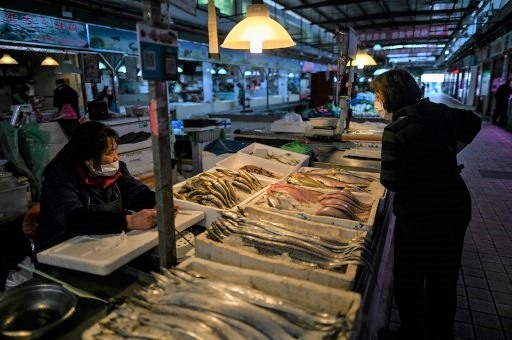 Tiểu thương và khách hàng đều đeo khẩu trang để ngăn chặn lây lan COVID-19 ở một chợ thủy sản ở Trung Quốc. Ảnh: AFP