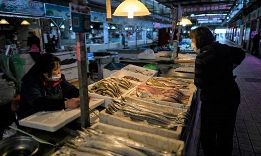Tiểu thương và khách hàng đều đeo khẩu trang để ngăn chặn lây lan COVID-19 ở một chợ thủy sản ở Trung Quốc. Ảnh: AFP
