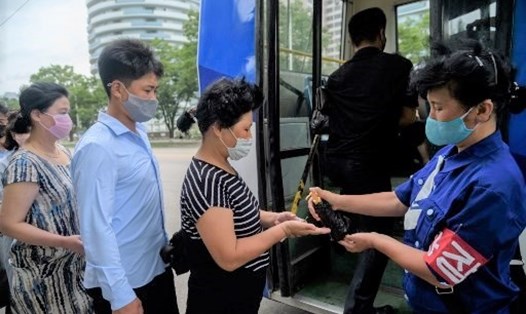 Hành khách nhận nước rửa tay từ nhân viên xe buýt để khử trùng COVID-19. Ảnh: AFP