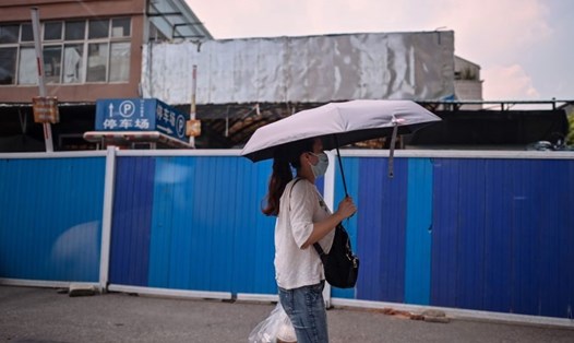 Người phụ nữ đi ngang qua chợ hải sản Huanan ở Vũ Hán, tỉnh Hồ Bắc vẫn bị đóng cửa. Ảnh: AFP