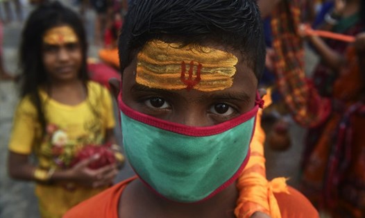 Một tín đồ đeo khẩu trang bắt đầu hành trình đến đền thờ Shiva sau khi ngâm mình và thực hiện các nghi lễ tại bờ sông Hằng, ở Kolkata, Ấn Độ trong bối cảnh đại dịch COVID-19 đang diễn biến phức tạp ở nước này. Ảnh: AFP