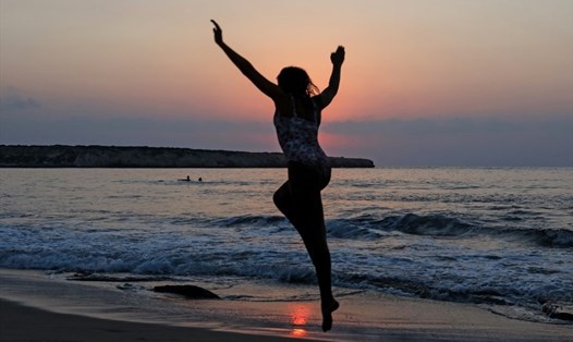 Một cô gái nhảy trên bãi biển Lara khi hoàng hôn ở phía đông đảo Cyprus hôm 21.8.2020. Ảnh: AFP.