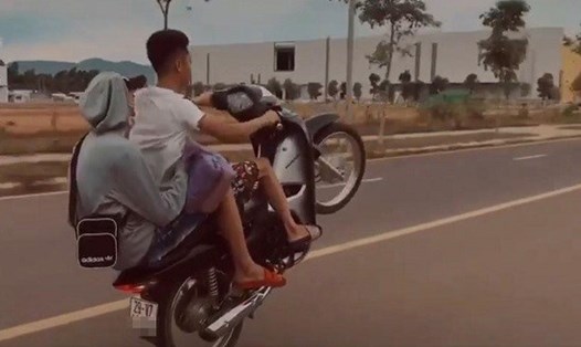 Hai thanh niên đi xe máy không đội mũ bảo hiểm, "bốc đầu" rồi đưa lên mạng xã hội. Ảnh: Cắt từ clip.