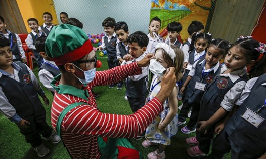 Một chú hề được trường mẫu giáo địa phương thuê hướng dẫn trẻ em cách đeo khẩu trang, nâng cao nhận thức về COVID-19 tại Gaza, Palestine. Ảnh: AFP.