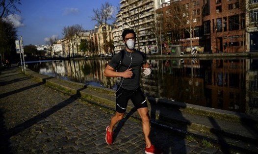 Để ngăn chặn dịch COVID-19 ở Pháp, Paris phát lệnh bắt buộc đeo khẩu trang ở ngoài trời. Trong ảnh là người đàn ông đeo khẩu trang chạy bộ dọc kênh Saint-Martin ở Paris. Ảnh: AFP.