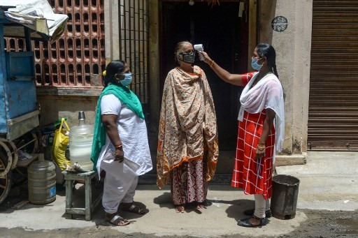 Nhân viên y tế đang đo thân nhiệt của người dân tại khu vực kiểm soát dịch bệnh ở thành phố Chennai, Ấn Độ, ngày 30.7, nhằm ngăn chặn và phòng ngừa COVID-19. Ảnh: AFP