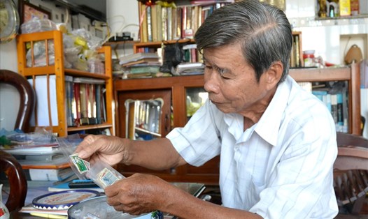 Ông Trần Hữu Huệ đang chuẩn bị tem tặng cho học sinh tại buổi sinh hoạt CLB chơi tem. Ảnh: Lục Tùng