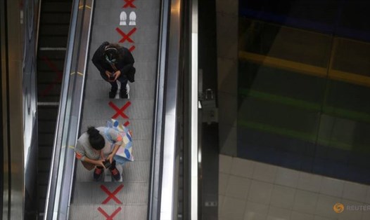 Các khách hàng đứng đúng vị trí chỉ dẫn trên thang cuốn để đảm bảo khoảng cách an toàn ngăn ngừa lây lan COVID-19, tại trung tâm thương mại Lima ở Peru. Ảnh: Reuters