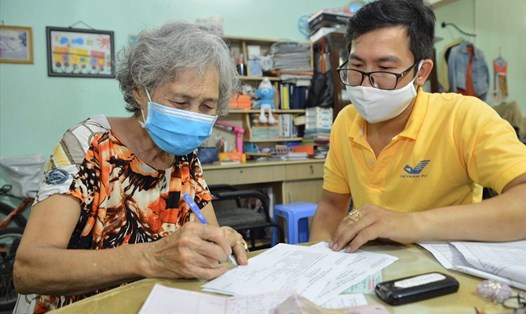 Cán bộ Bưu điện Việt Nam thực hiện chi trả lương hưu tại nhà cho người dân. 
Ảnh: A.M