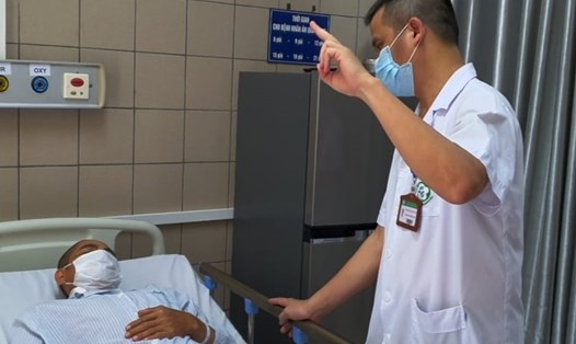 TS.BS Nguyễn Trung Nguyên kiểm tra thị lực của bệnh nhân ngộ độc methanol. Ảnh: Mai Thanh.