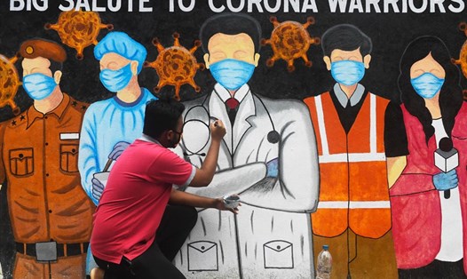 Vẽ tranh cổ động các bác sĩ tuyến đầu chống dịch COVID-19 ở Ấn Độ. Ảnh: AFP