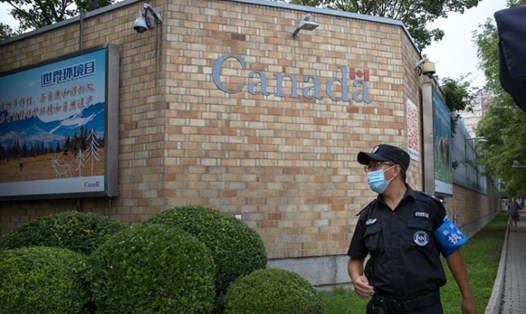 Một nhân viên an ninh đeo khẩu trang đứng bên ngoài Đại sứ quán Canada ở Bắc Kinh, Trung Quốc, hôm 6.8. Ảnh: AP.