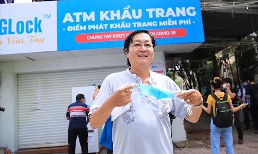 Người dân tiếp nhận khẩu trang từ điểm “ATM khẩu trang miễn phí” của anh Hoàng Tuấn Anh. Ảnh: Phạm Đông - Hữu Huy