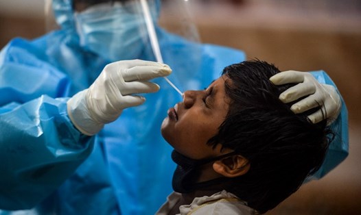 Một nhân viên y tế lấy mẫu xét nghiệm COVID-19 cho một bé trai tại trung tâm ở Samarnagar, Siliguri, Ấn Độ hôm 9.9. Ảnh: AFP.