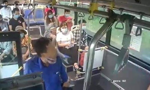 Người đàn ông (áo xanh) nhổ nước bọt vào nữ phụ xe bus khi chị này nhắc nhở anh ta đeo khẩu trang, được camera ghi lại. Ảnh cắt từ clip.
