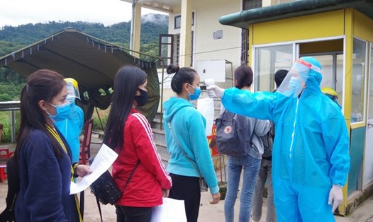 Lực lượng y tế kiểm tra thân nhiệt cho du học sinh nhập cảnh, sau đó lên xe đi đến khu cách ly tập trung ở Thừa Thiên Huế. Ảnh: thuathienhue.gov.vn.
