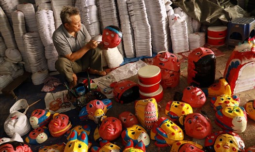 Nghệ nhân Vũ Huy Đông đang tranh thủ sơn màu những chiếc mặt nạ bồi cho chuyến hàng Tết Trung thu. Ảnh: Hải Nguyễn