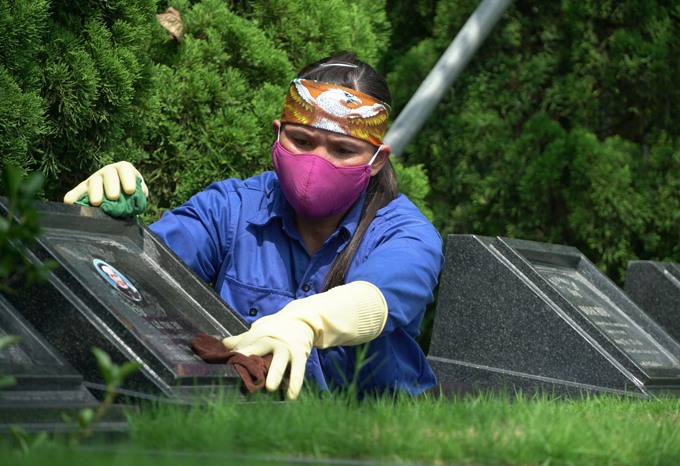 Chị Bùi Thị Thêm đang lau dọn mộ phần. Ảnh: Huyền Chang