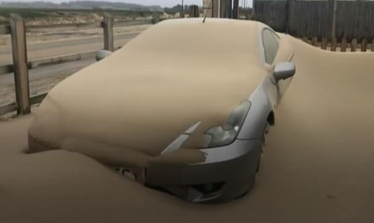 Một chiếc xe ô tô bị ngập trong đống cát lớn sau khi bão cát tấn công. Ảnh: Daily Mail