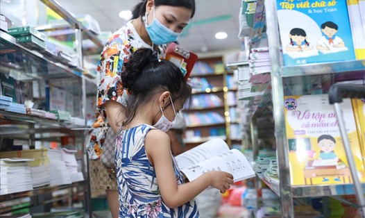 Phụ huynh đưa con chọn sách giáo khoa và sách tham khảo lớp 1 tại một nhà sách ở Hà Nội. Ảnh: Hải NGuyễn