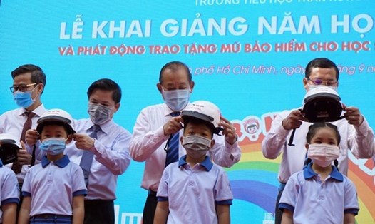 Đồng chí Trương Hòa Bình và các đại biểu trao tặng mũ bảo hiểm đạt chuẩn cho học sinh Trường Tiểu học Trần Hưng Đạo. Ảnh: Hùng Khoa