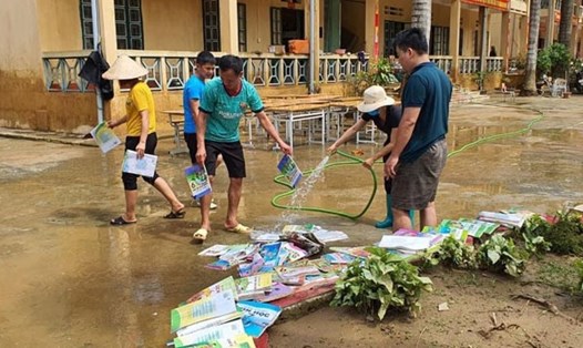 Phụ huynh học sinh hỗ trợ nhà trường rửa sách giáo khoa cho học sinh. Ảnh: Phạm Vũ Sơn