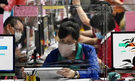 Người dân đeo khẩu trang ngồi tại bàn có vách ngăn nhựa tại cơ quan thuế ở Đài Bắc, Đài Loan, được dựng lên trong bối cảnh dịch COVID-19. Ảnh: AFP.