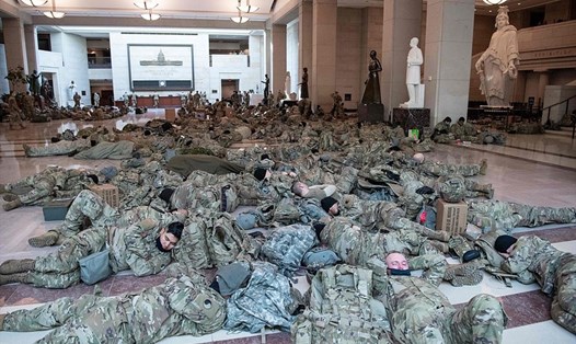 Lính Vệ binh Quốc gia Mỹ ngủ trên sàn của Điện Capitol ngày Hạ viện Mỹ họp ngày 13.1. Ảnh: AFP.