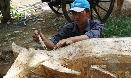 Nghệ nhân Nho Hòa Thanh (60 tuổi, người tạo hình linh vật đường hoa Nguyễn Huệ)  đang xé vỏ tràm để đắp lên linh vật trâu vừa được phủ một lớp keo trước đó. Ảnh: Thanh Chân.