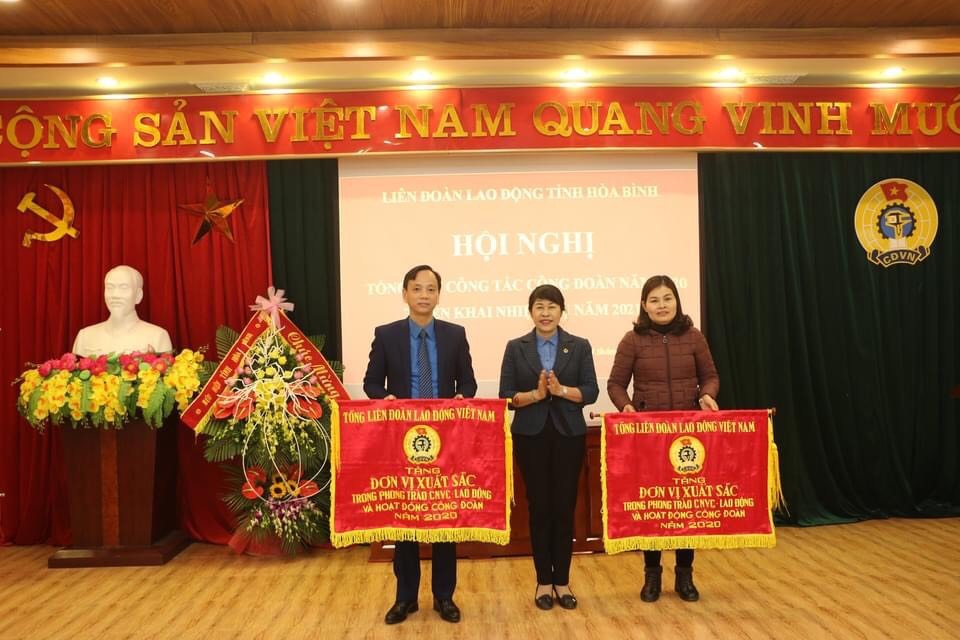 Đồng chí Trịnh Thanh Hằng, Trưởng Ban nữ công Tổng Liên đoàn Lao động Việt Nam trao cờ cho đơn vị LĐLĐ huyện Lạc Sơn và Công đoàn Viên chức tỉnh. Ảnh: Mạnh Cường