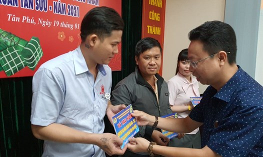 Ông Nguyễn Thành Đô - Trưởng Ban Chính sách-Pháp luật LĐLĐ TPHCM - trao vé tàu cho gia đình các công nhân về quê ăn Tết. Ảnh: Nam Dương
