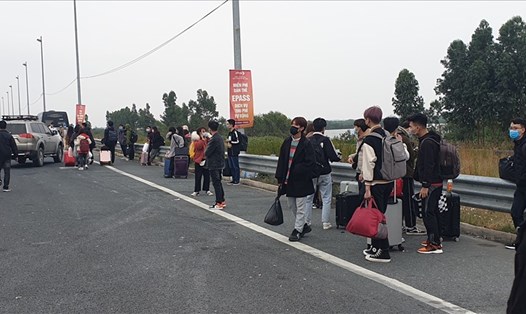 Một nhóm học sinh, sinh viên đợi xe để về nhà trước Trạm thu phí cầu Bạch Đằng chiều tối 30.1.2021. Ảnh: Nguyễn Hùng