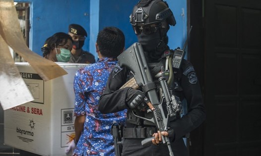 Cảnh sát có vũ trang hộ tống nhân viên dỡ vaccine COVID-19 của Sinovac trên xe tải ở Surabaya, Indonesia, hôm 4.1. Ảnh: AFP.