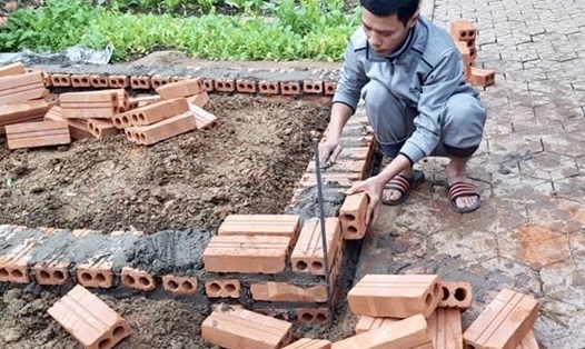 Thầy Vũ Xuân Quế trực tiếp tham gia lát gạch để xây lò ủ nước nóng cho học sinh. Ảnh: NVCC