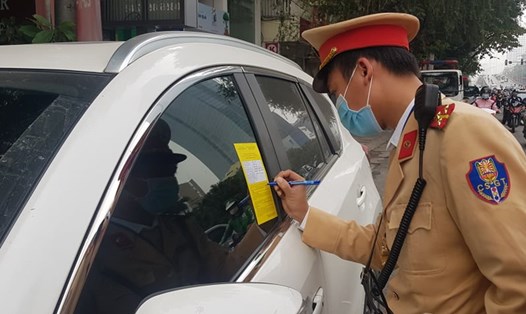Cảnh sát giao thông Hà Nội dán giấy phạt nguội lên kính các xe ôtô dừng, đỗ sai quy định. Ảnh: V.Dũng.