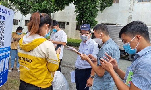 Nhân viên Cty Nissei Electric Việt Nam (đội mũ) hướng dẫn cho lao động mới được tuyển dụng khai báo y tế trước khi vào làm việc sáng 13.10. Ảnh: Nam Dương