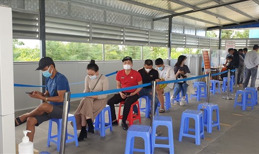 Người dân xếp hàng đợi xuất trình giấy tờ tùy thân, sau khi đã khai báo y tế qua PC-COVID chiều 16.10 tại Chốt kiểm soát cầu Bạch Đằng. Ảnh: Nguyễn Hùng