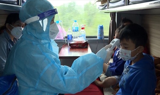 Nữ y tá Tạ Thị Phúc kiểm tra thân nhiệt của người dân khi lên tàu về quê Quảng Trị. Ảnh: Quốc Nhật.
