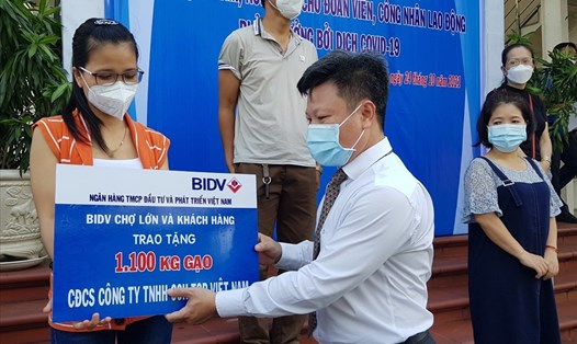 Đại diện Ngân hàng BIDV chi nhánh Chợ Lớn trao biển tượng trưng tặng gạo cho công nhân Khu chế xuất Tân Thuận. Ảnh: Nam Dương