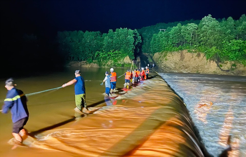 Lực lượng cứu hộ dàn hàng trên con đập ngập nước lũ để đưa 3 thanh niên rời khỏi nơi bị cô lập. Ảnh: Công an tỉnh Quảng Trị.