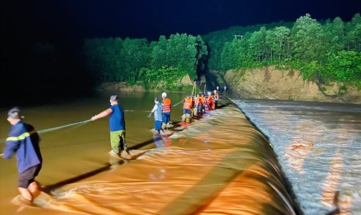 Lực lượng cứu hộ dàn hàng trên con đập ngập nước lũ để đưa 3 thanh niên rời khỏi nơi bị cô lập. Ảnh: Công an tỉnh Quảng Trị.