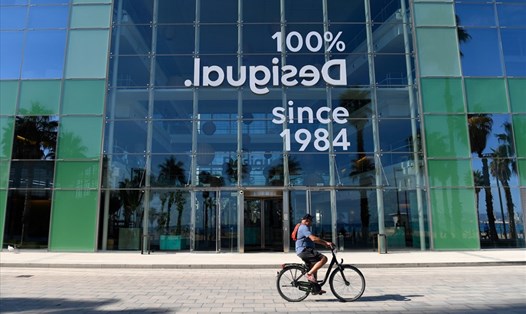 Một người đàn ông đạp xe ngang qua trụ sở của một công ty ở Barcelona, Tây Ban Nha. Ảnh minh họa: AFP