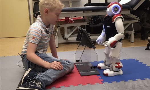 Cậu bé mắc bệnh tiểu đường người Hà Lan Ruben van As, 7 tuổi, chơi với robot Charlie khi robot đang dạy cậu bé cách ứng phó với bệnh tại bệnh viện Gelderse Vallei ở Ede, Hà Lan năm 2016. Ảnh: AFP