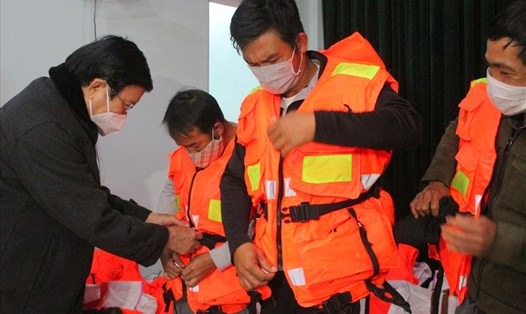 Nguyên Chủ tịch nước Trương Tấn Sang hướng dẫn ngư dân mặc áo phao cứu sinh. Ảnh: NH.