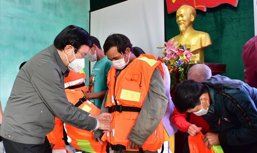 Nguyên Chủ tịch nước Trương Tấn Sang hướng dẫn ngư dân mặc áo phao cứu sinh. Ảnh: N. Minh.