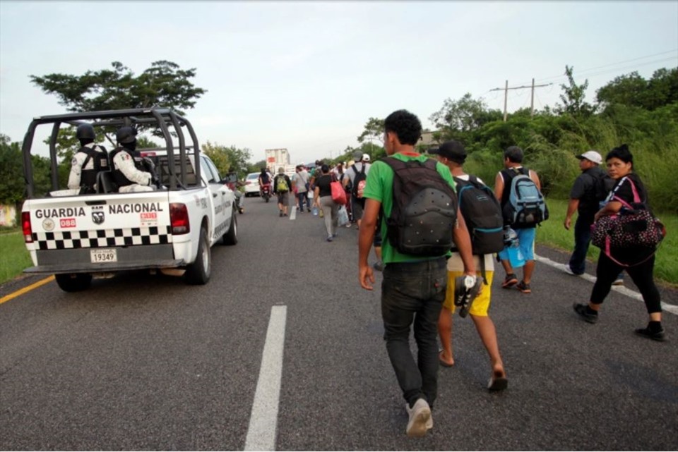 Xe tải của Lực lượng Vệ binh Quốc gia đi gần một đoàn người di cư đang hướng về thành phố Pijijiapan, Mexico. Ảnh: AFP