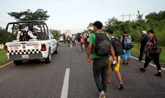 Xe tải của Lực lượng Vệ binh Quốc gia đi gần một đoàn người di cư đang hướng về thành phố Pijijiapan, Mexico. Ảnh: AFP